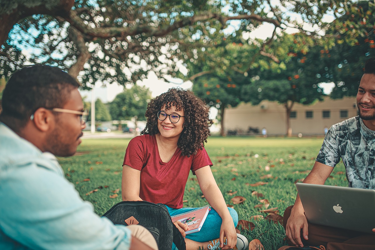 Three adult students sitting outdoors.